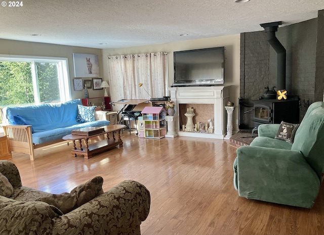 living room featuring a wood stove, wood-type flooring, and a textured ceiling