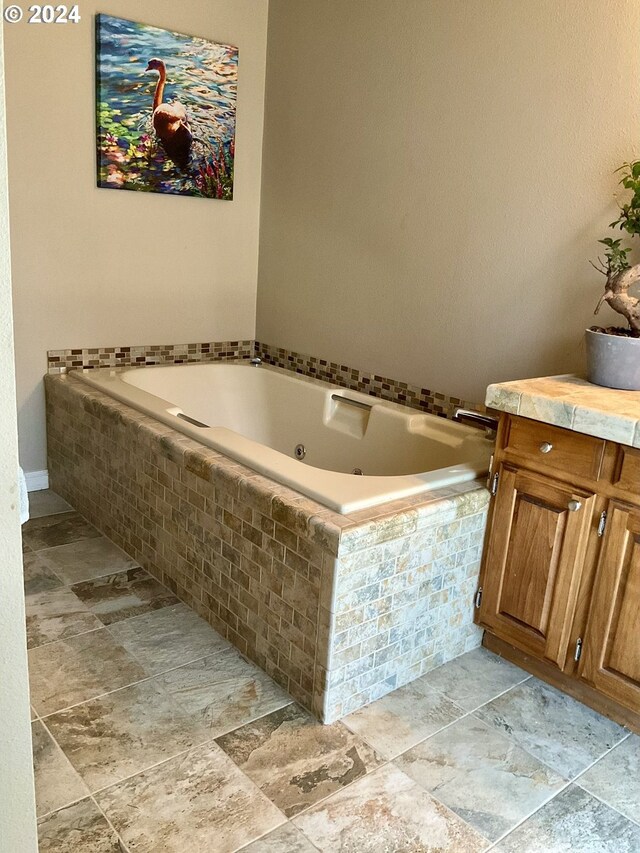 bathroom with tiled tub and vanity