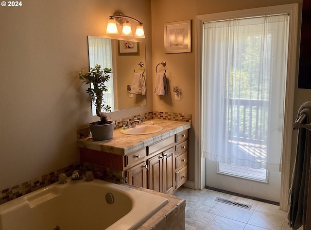 bathroom with tile patterned flooring, tiled bath, and vanity