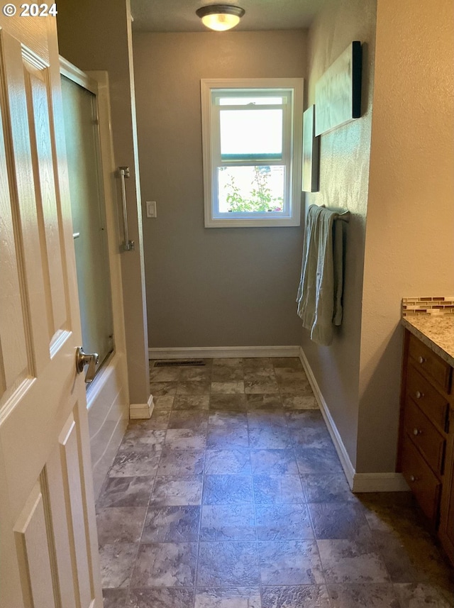 bathroom featuring vanity and bath / shower combo with glass door