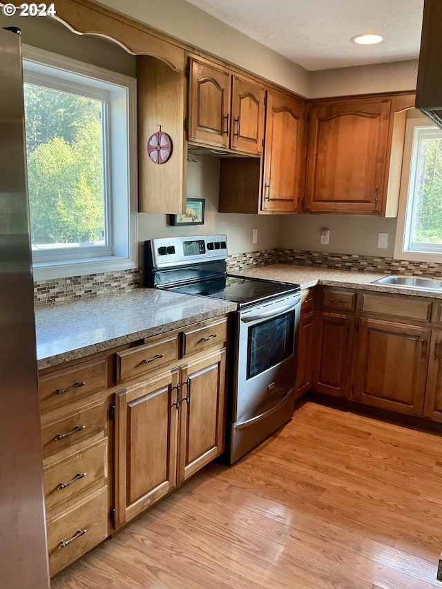 kitchen with appliances with stainless steel finishes, light hardwood / wood-style floors, and sink