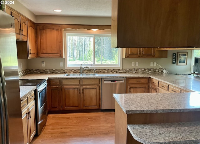 kitchen featuring a textured ceiling, light hardwood / wood-style flooring, stainless steel appliances, sink, and kitchen peninsula