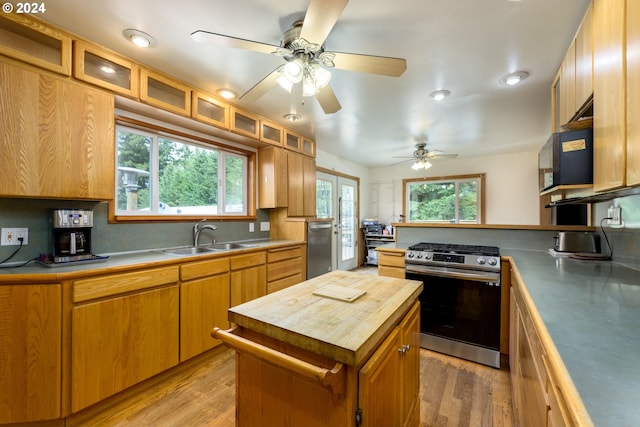 kitchen featuring appliances with stainless steel finishes, light wood-type flooring, backsplash, sink, and a kitchen island