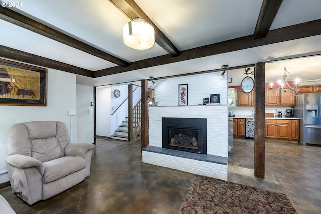 living room with beam ceiling, an inviting chandelier, and a brick fireplace