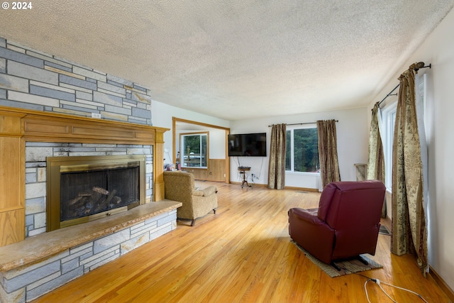 living room with a textured ceiling, light hardwood / wood-style floors, and a fireplace