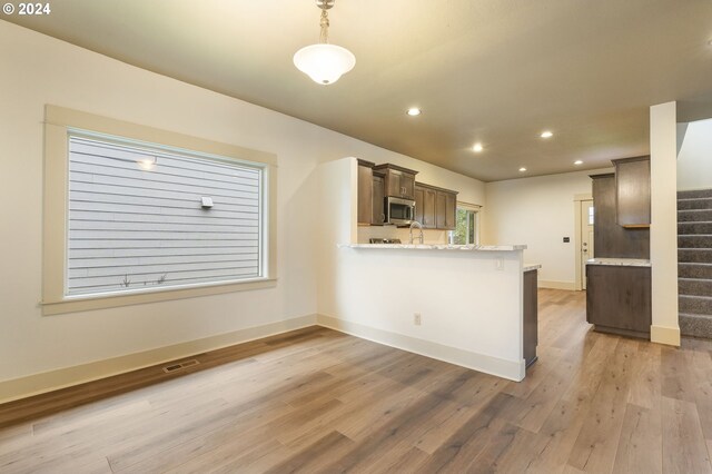 kitchen featuring light stone counters, light hardwood / wood-style flooring, sink, stainless steel appliances, and dark brown cabinetry