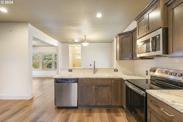 kitchen with stainless steel appliances, sink, light wood-type flooring, and dark brown cabinetry