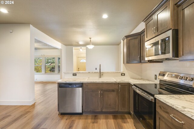 kitchen with light wood-type flooring, light stone counters, and dark brown cabinetry