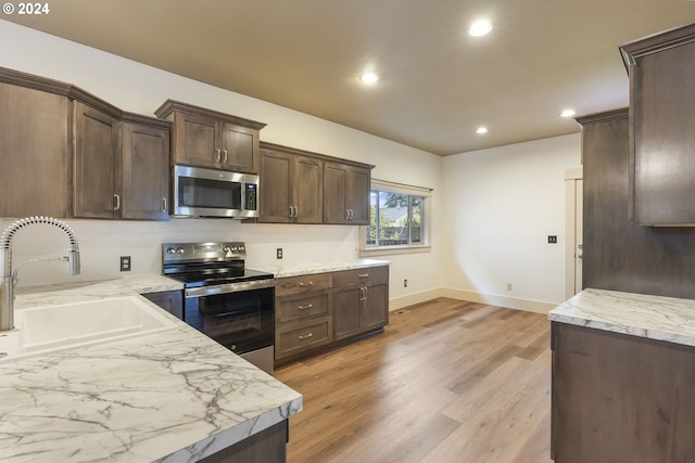 kitchen with sink, stainless steel appliances, light hardwood / wood-style floors, and dark brown cabinetry