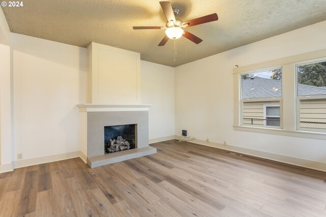 unfurnished living room with a textured ceiling, ceiling fan, and light wood-type flooring