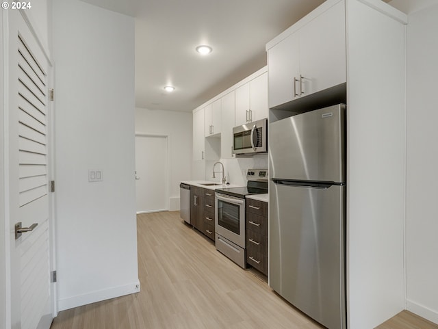 kitchen with light hardwood / wood-style flooring, white cabinets, appliances with stainless steel finishes, dark brown cabinets, and sink