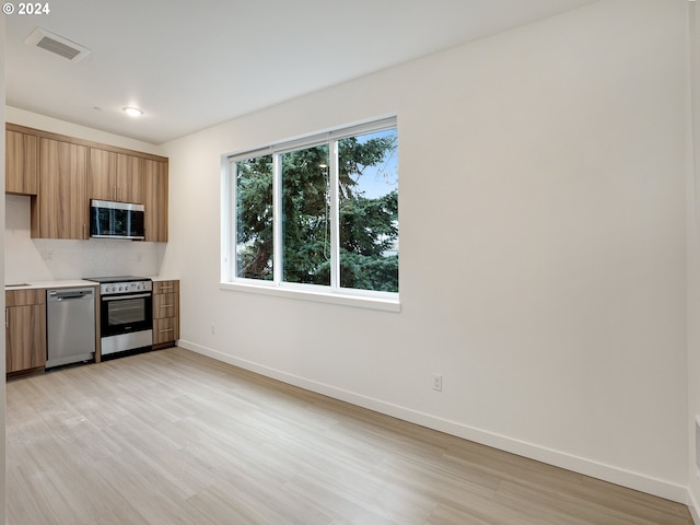 kitchen featuring stainless steel appliances, light wood-type flooring, and tasteful backsplash