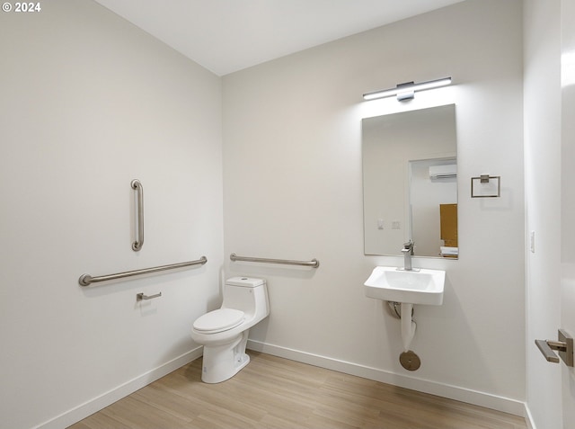 bathroom with sink, toilet, hardwood / wood-style flooring, and an AC wall unit