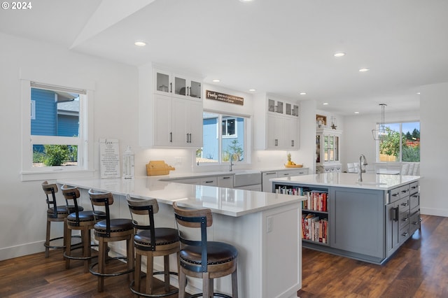 kitchen featuring a healthy amount of sunlight, kitchen peninsula, and white cabinets