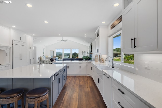 kitchen featuring ceiling fan, lofted ceiling, sink, paneled built in fridge, and a kitchen bar