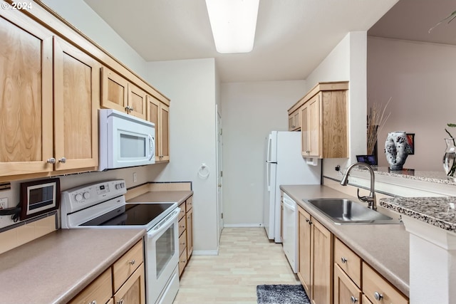 kitchen featuring white appliances, light brown cabinetry, and sink