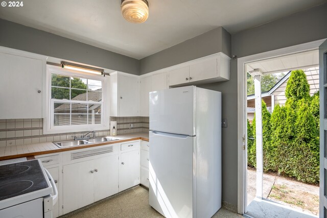 kitchen featuring decorative backsplash, a wealth of natural light, white appliances, and white cabinets