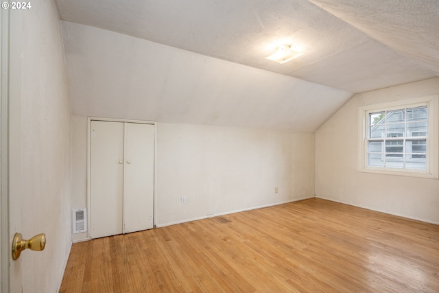 bonus room with light hardwood / wood-style flooring, lofted ceiling, and a textured ceiling