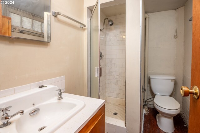 bathroom featuring a tile shower, vanity, and toilet