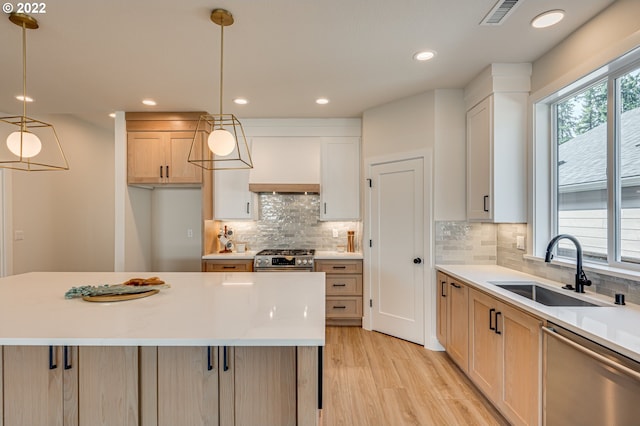 kitchen with light wood-type flooring, a center island, sink, hanging light fixtures, and stainless steel appliances