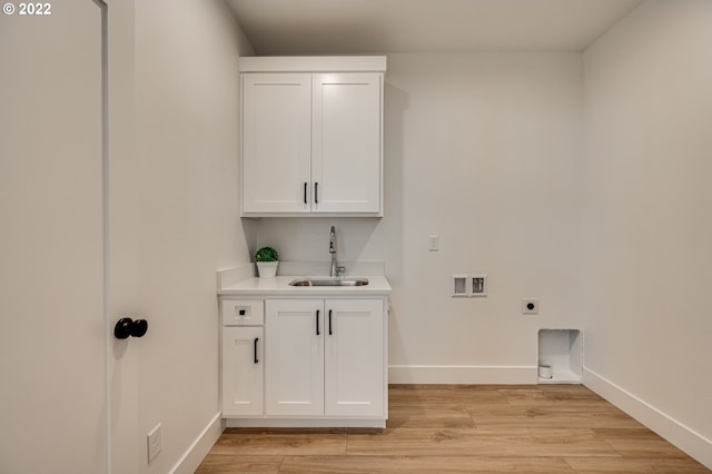 washroom with hookup for a washing machine, hookup for an electric dryer, light hardwood / wood-style flooring, cabinets, and sink