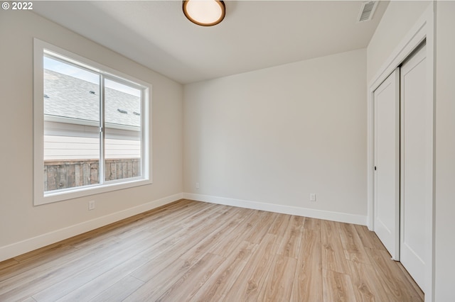 unfurnished bedroom with multiple windows, light hardwood / wood-style flooring, and a closet