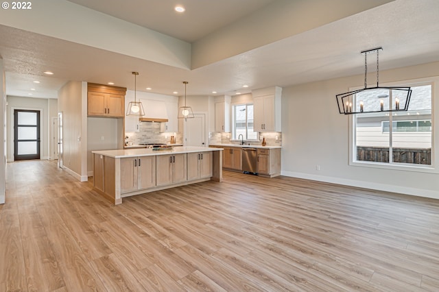 kitchen with pendant lighting, dishwasher, tasteful backsplash, a kitchen island, and light hardwood / wood-style flooring