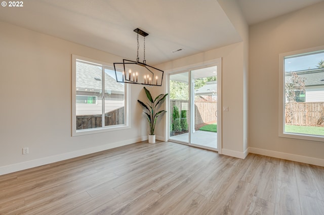 unfurnished dining area featuring light hardwood / wood-style floors and a notable chandelier