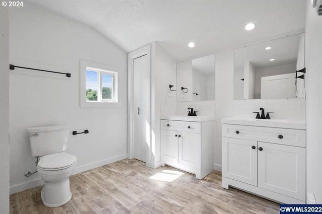 bathroom featuring toilet, vaulted ceiling, hardwood / wood-style flooring, tasteful backsplash, and vanity