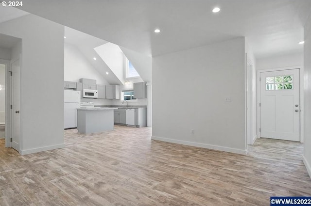 unfurnished living room featuring vaulted ceiling and light hardwood / wood-style floors