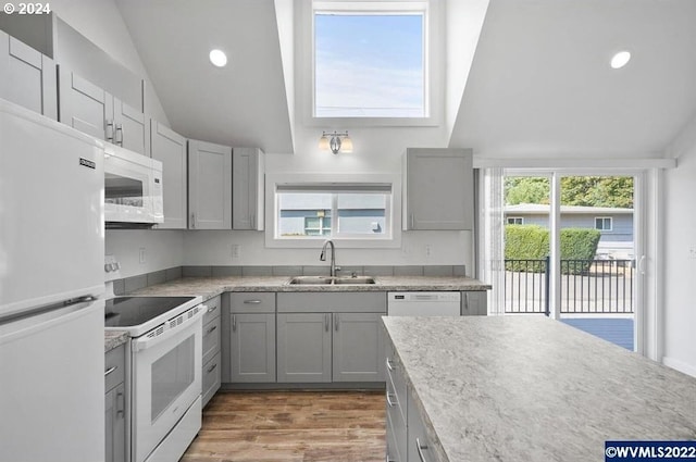 kitchen with sink, gray cabinetry, white appliances, and vaulted ceiling