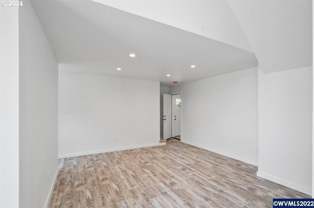 spare room with light wood-type flooring and vaulted ceiling