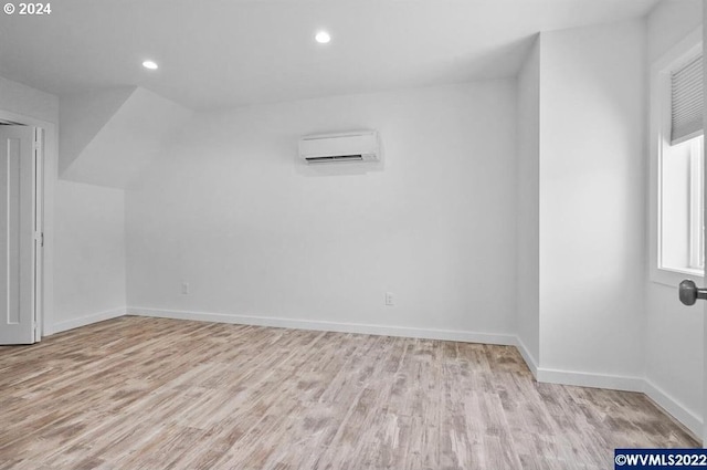 bonus room with a wall mounted AC and light hardwood / wood-style floors