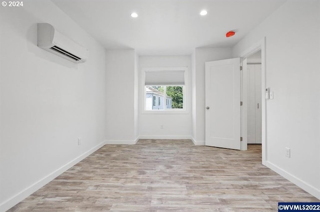 spare room featuring a wall unit AC and light hardwood / wood-style flooring