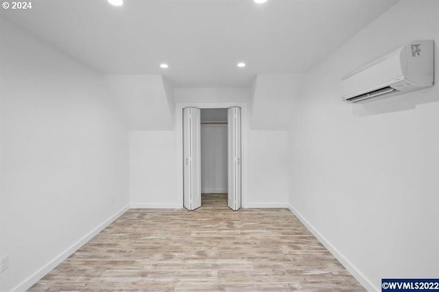 unfurnished bedroom with light hardwood / wood-style floors and a wall mounted AC