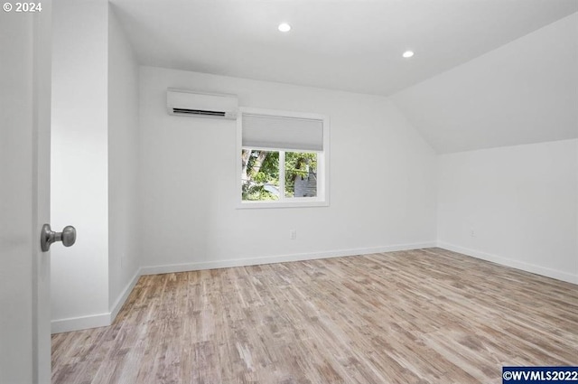 bonus room featuring light hardwood / wood-style floors, vaulted ceiling, and a wall mounted air conditioner