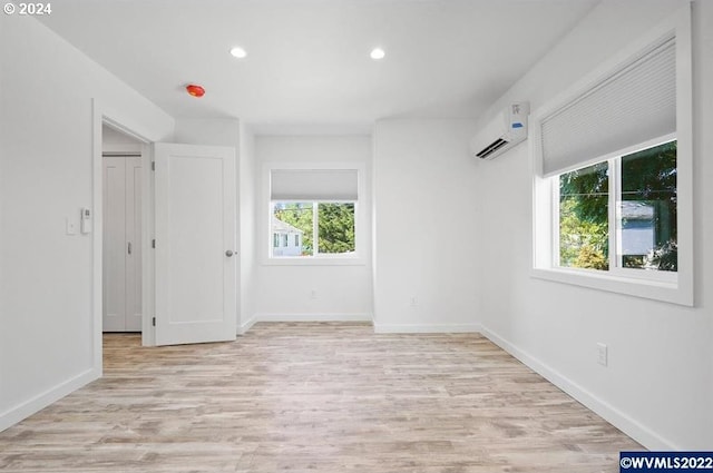 unfurnished room with an AC wall unit and light wood-type flooring