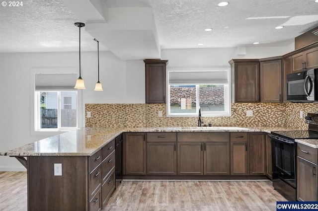 kitchen featuring pendant lighting, a wealth of natural light, black appliances, and kitchen peninsula