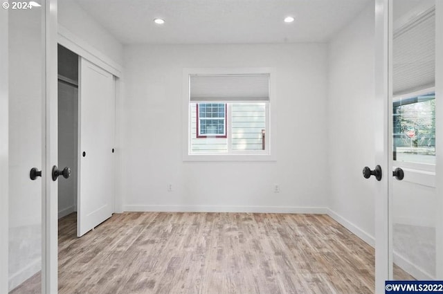 unfurnished bedroom with light hardwood / wood-style floors and french doors