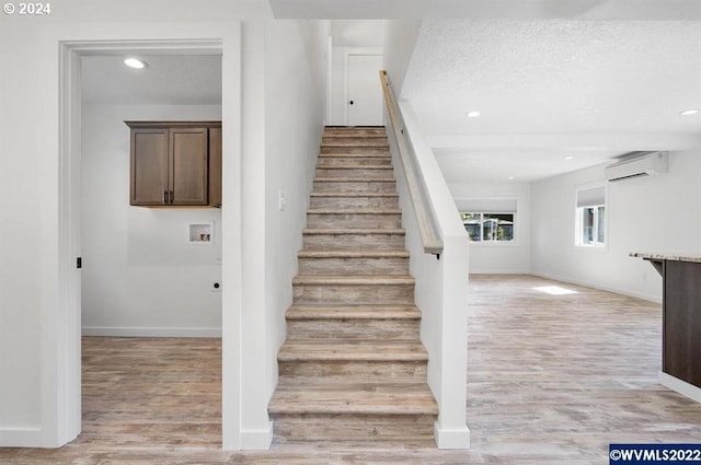 stairs featuring a wall mounted AC, wood-type flooring, and a textured ceiling