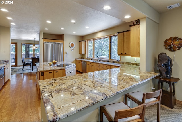 kitchen with visible vents, a kitchen island, appliances with stainless steel finishes, a peninsula, and recessed lighting