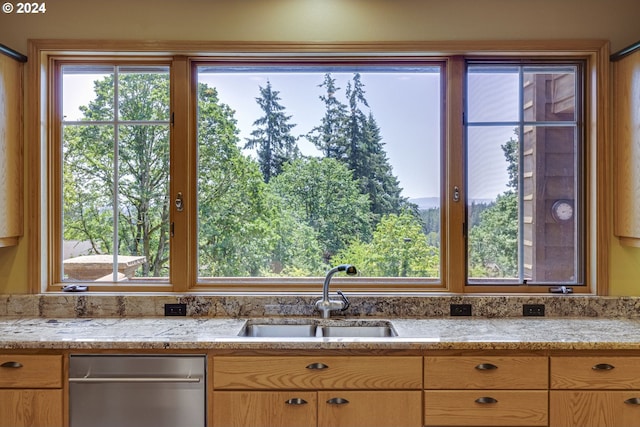 kitchen featuring dishwasher, light stone counters, and a sink