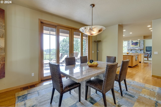 dining room with a textured ceiling, recessed lighting, visible vents, baseboards, and light wood-style floors