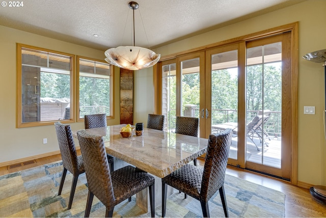 dining space with french doors, visible vents, light wood-style floors, a textured ceiling, and baseboards