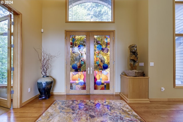 entrance foyer featuring a wealth of natural light, french doors, a towering ceiling, and light hardwood / wood-style floors