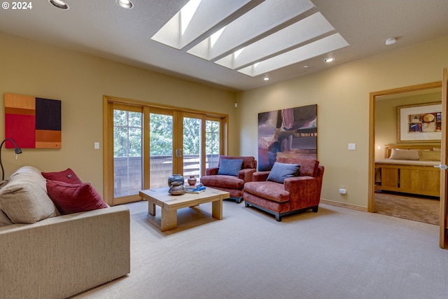 living room featuring recessed lighting, light colored carpet, a skylight, baseboards, and french doors