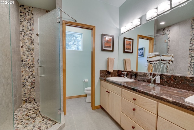 bathroom with double vanity, toilet, a sink, a shower stall, and baseboards