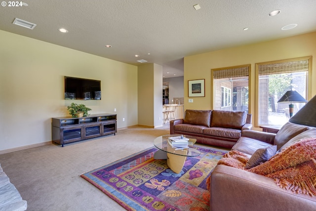 living room with a textured ceiling, carpet flooring, visible vents, and baseboards