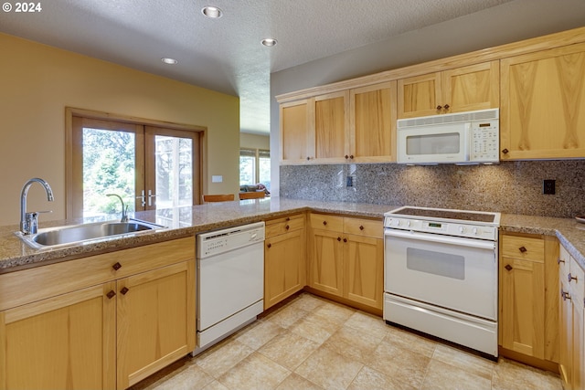 kitchen featuring light countertops, decorative backsplash, light brown cabinets, a sink, and white appliances