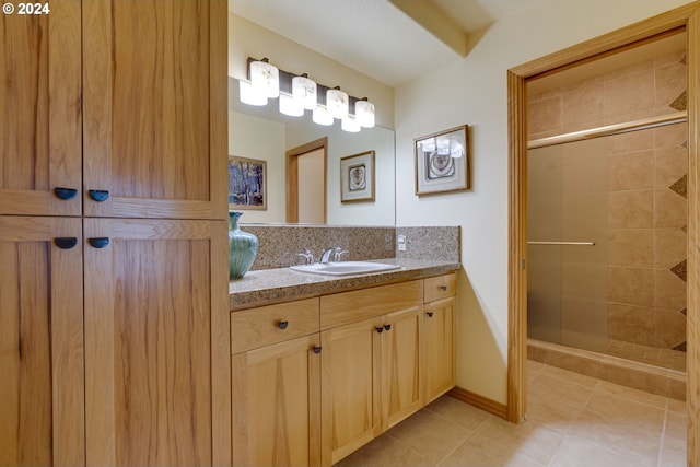 bathroom featuring baseboards, a tile shower, vanity, and tile patterned floors